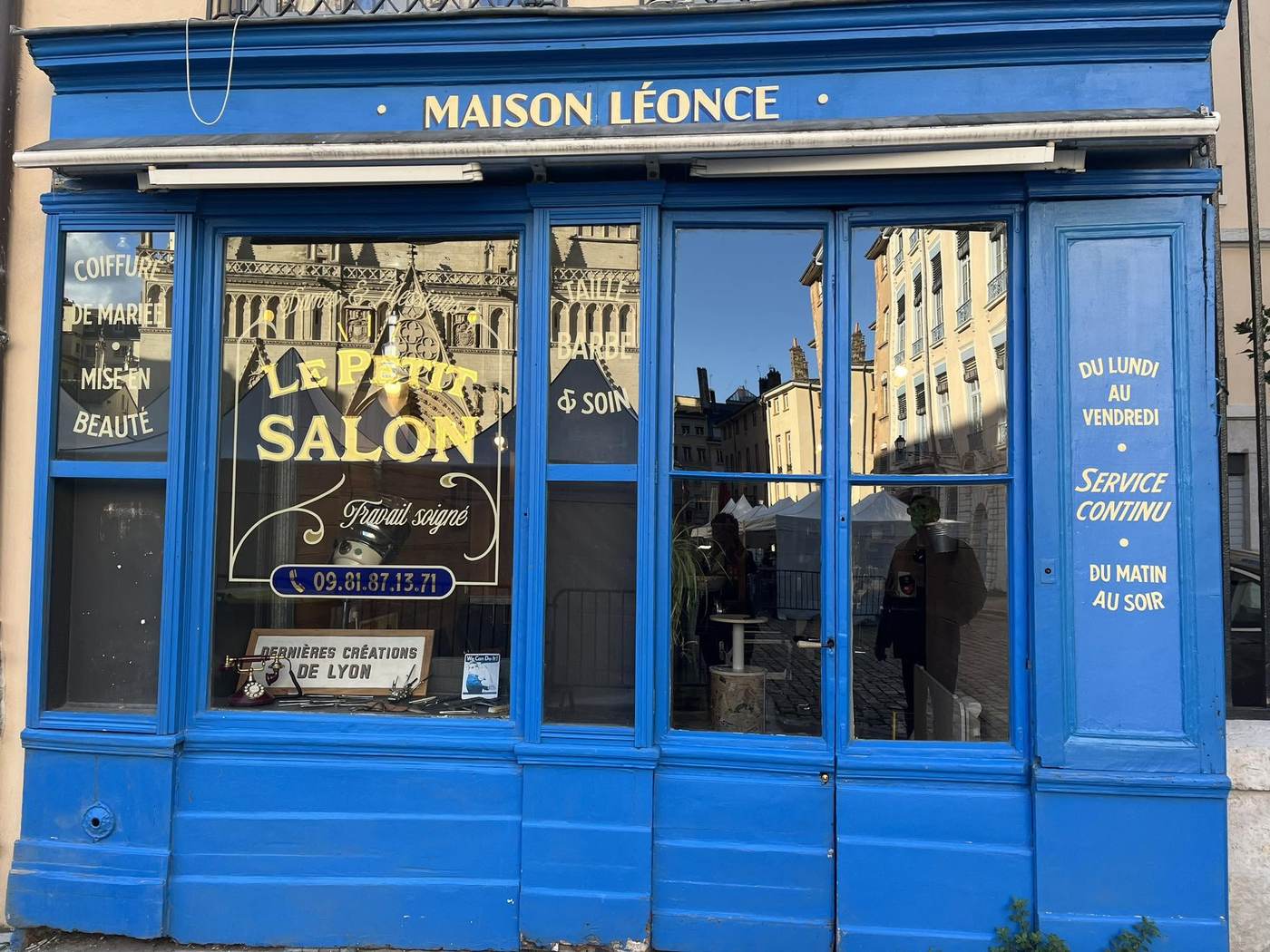 La vitrine peinte de Maison Léonce, 6 place Saint-Jean à Lyon, avec la cathédrale Saint-Jean reflétée dans les vitres